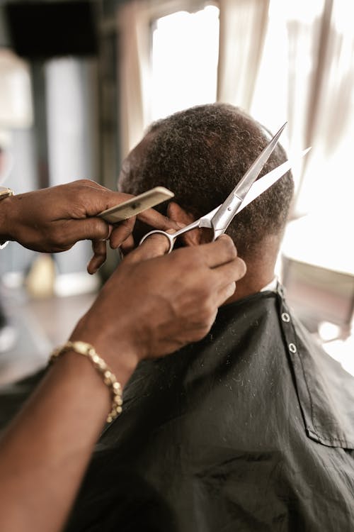 Person Cutting a Man's Hair using Scissors