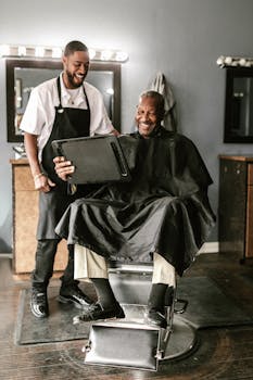 A joyful moment captured between a barber and his smiling client during a haircut session.