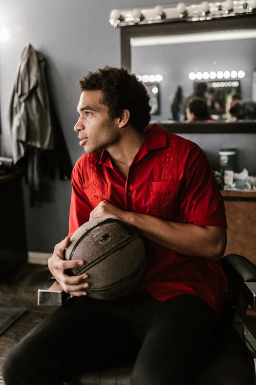 A Man Holding a Basketball while Sitting in a Barber Chair