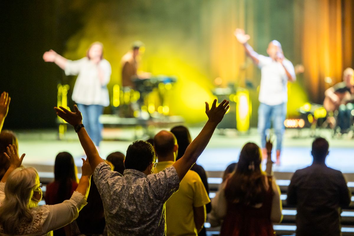 An excited concert audience with hands raised, enjoying a live performance