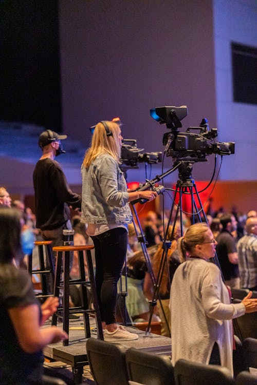 Side view of operators with cameras recording video during performance in concert room