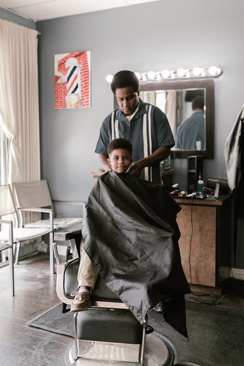 Boy in Cape Sitting in Barbers Chair