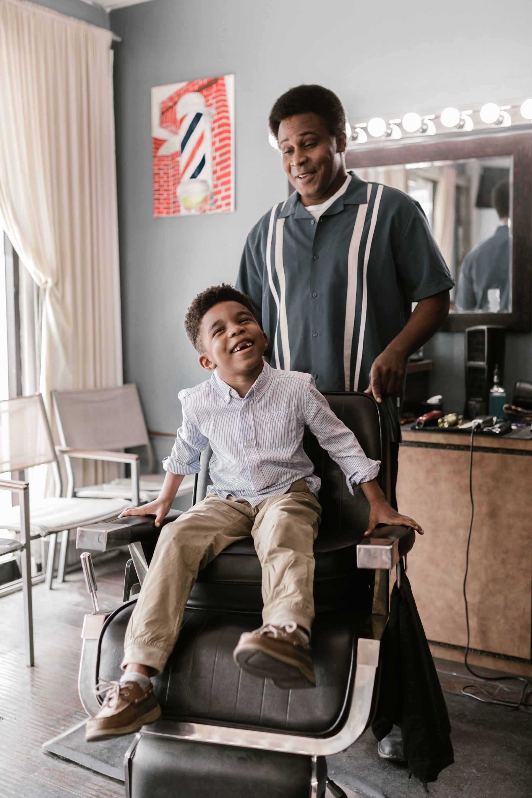Barber checking the final cut while a family member waits nearby
