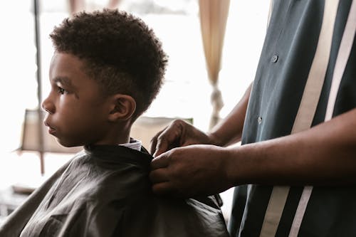 A Child Wearing a Barber's Cape