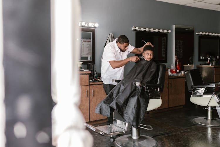 Barber Serving Little Black Boy In Barbershop