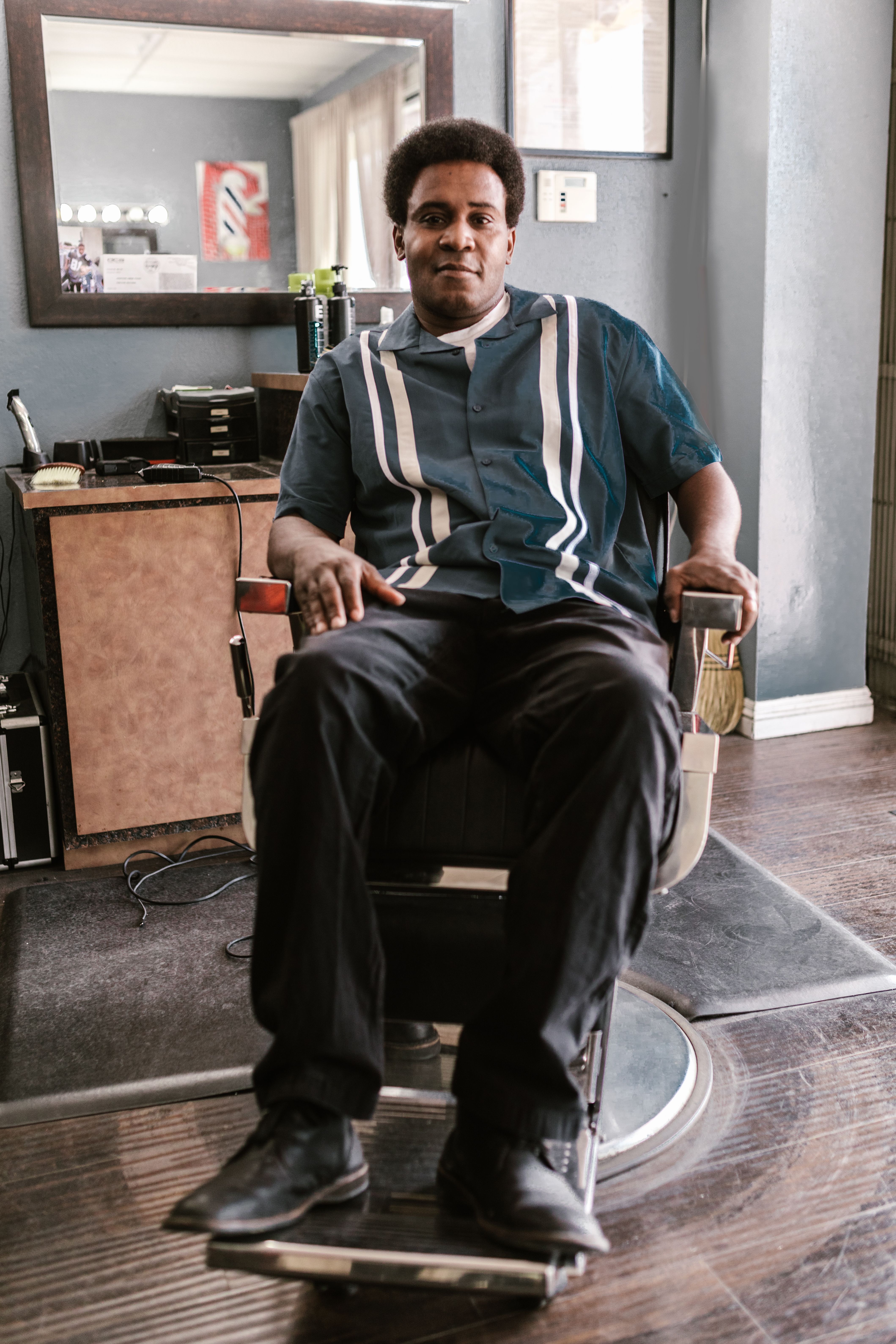 Man sitting comfortably in a barber chair inside a cozy barber shop.