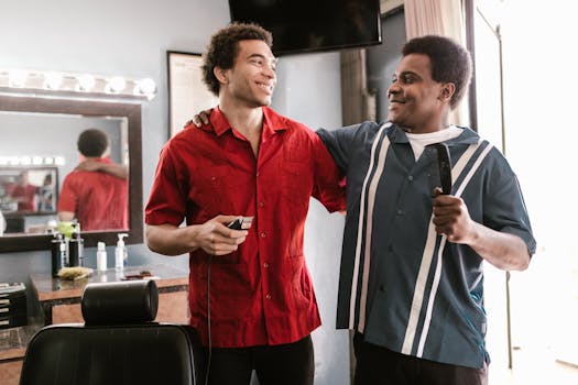 Two smiling barbers sharing a moment of camaraderie inside a barber shop.
