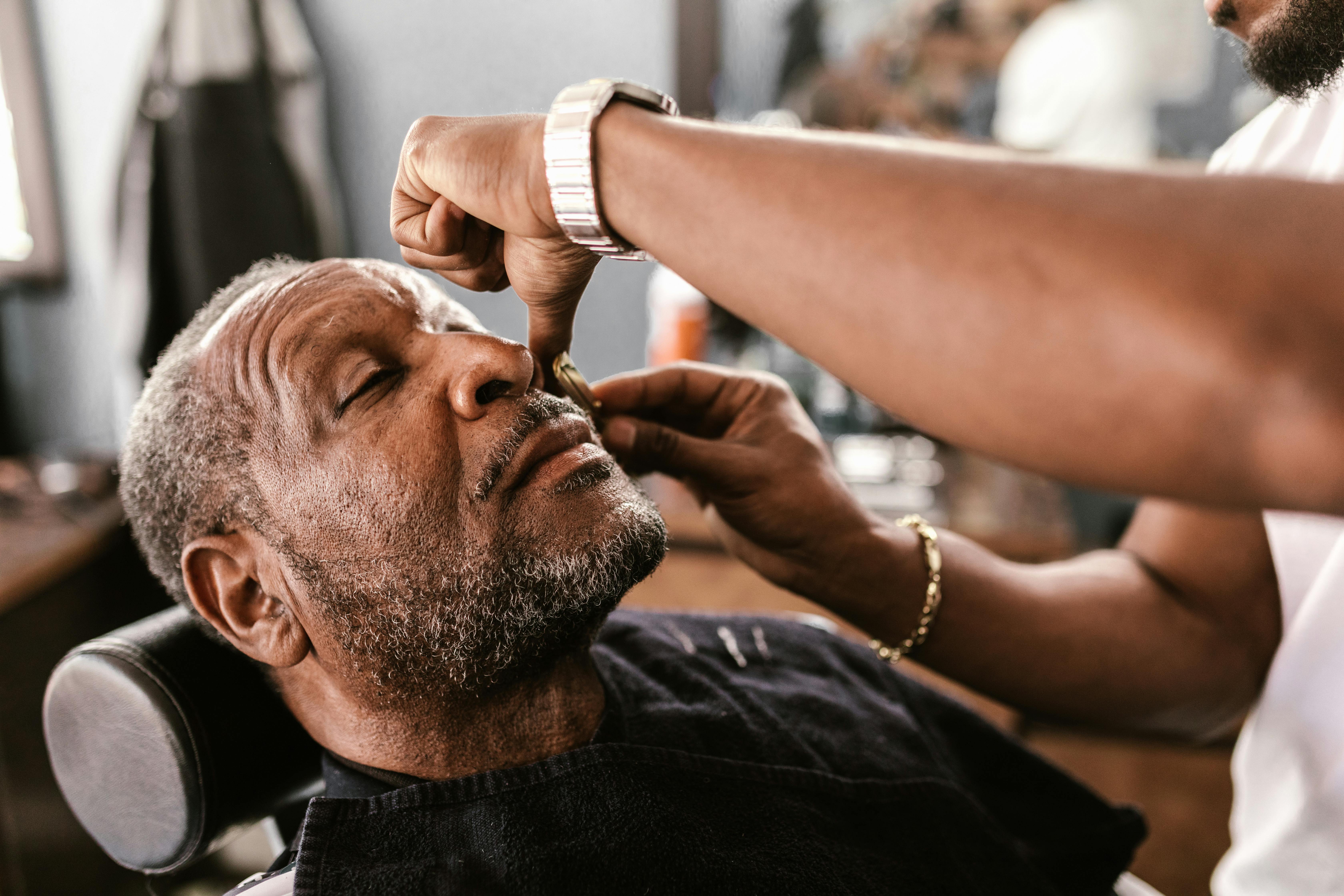 A senior man enjoys a professional grooming session at a barbershop, showcasing detailed craftsmanship.
