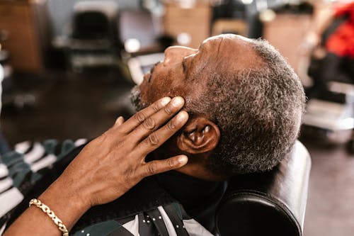 Mature Black Man Relaxing in Chair in Barbershop