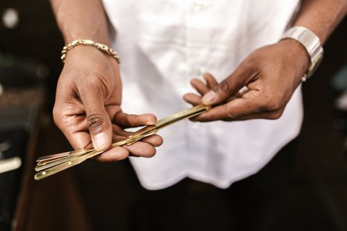 Free A detailed close-up of a person holding elegant golden razors, highlighting vintage grooming tools. Stock Photo