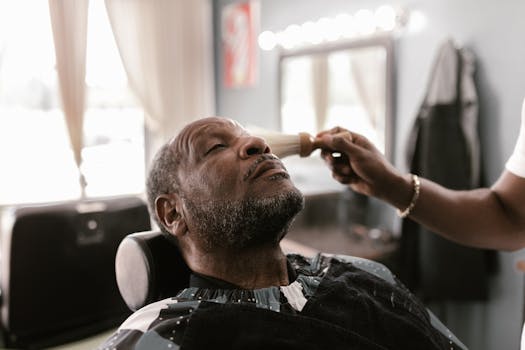 A close-up view of a barber using a neck duster on an adult male client in a barbershop setting.