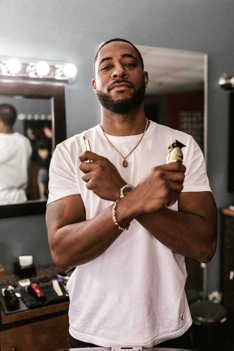 Barber holding clippers and a straight razor in the shop