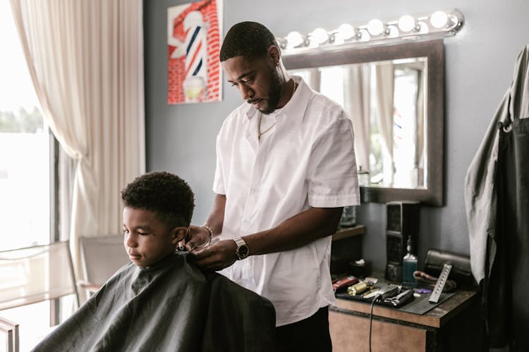 A Man Clipping A Boy's Barber Cape