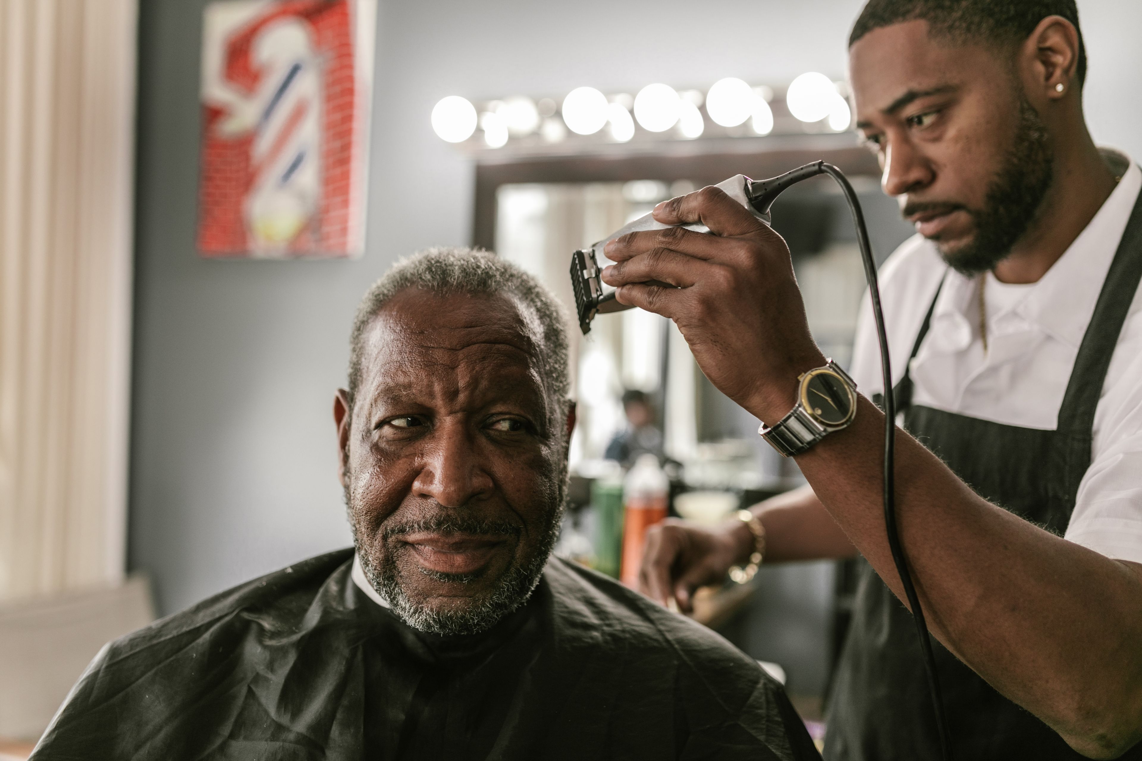 A barber trimming a client’s beard in his shop