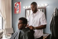 A barber preparing to cut his customer's hair in a stylish barbershop setting.