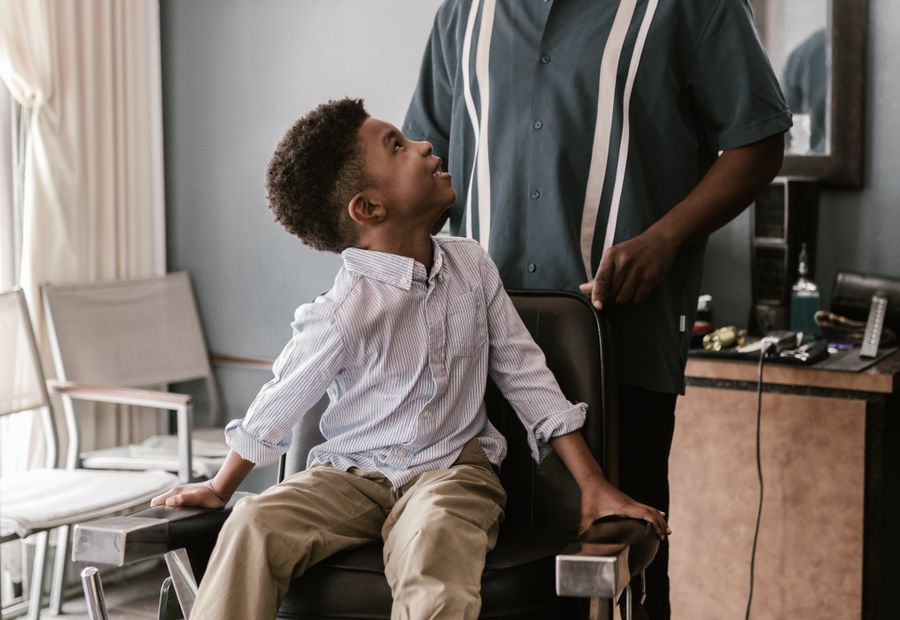 A boy sitting on a barber chair