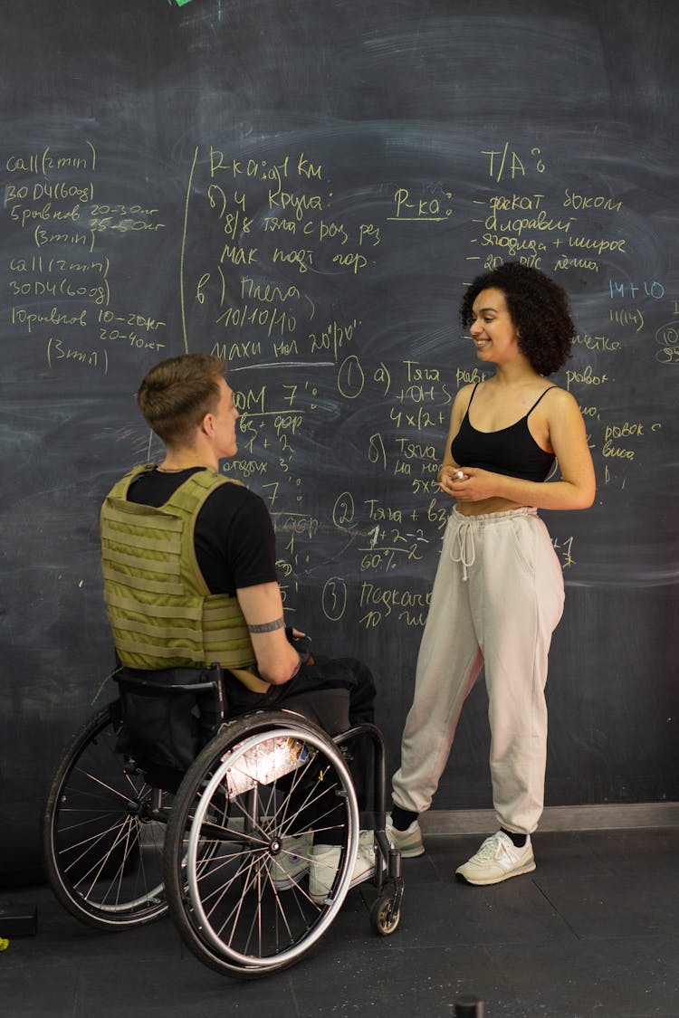 A Personal Trainer Talking To Her Client By A Chalkboard