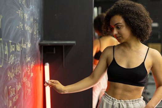 African American woman writing on a chalkboard with focus on education in a casual setting.