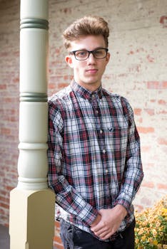 一个戴眼镜、穿格子衬衫的年轻人靠在柱子上