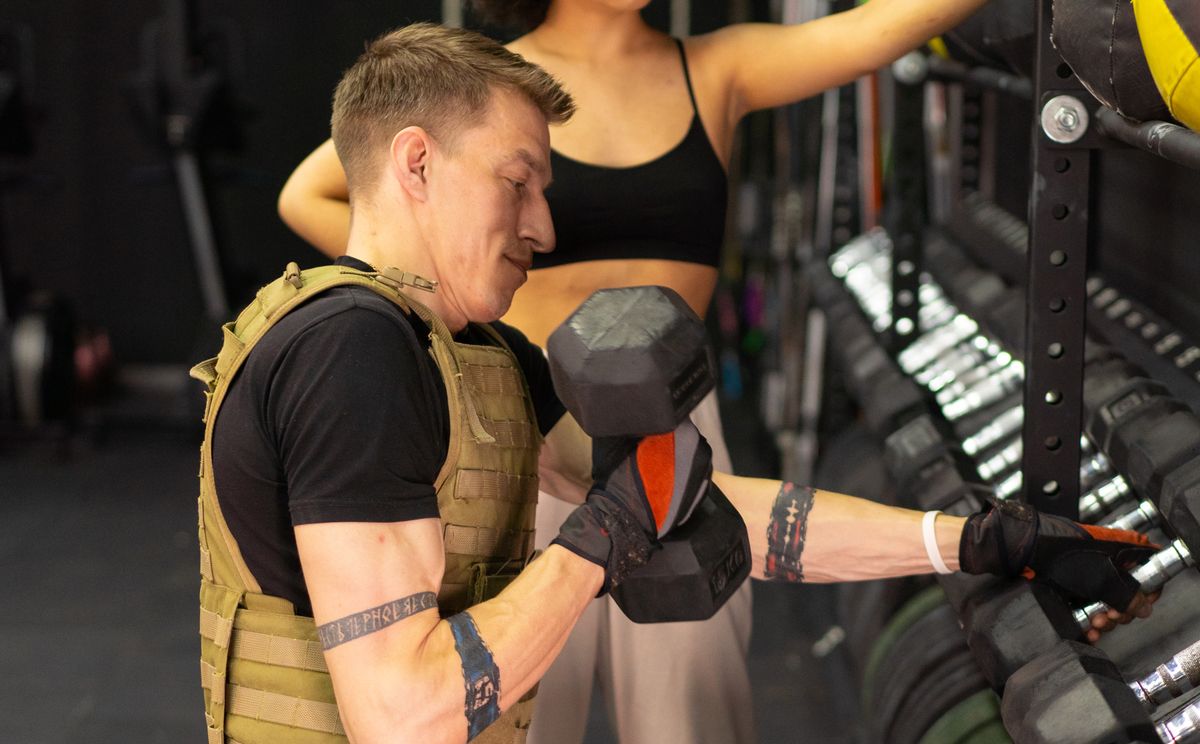 Man in a weighted vest holding a dumbbell during a strength training workout