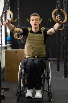 A focused athlete in a wheelchair performs exercises with gymnastic rings indoors, showcasing strength and determination.