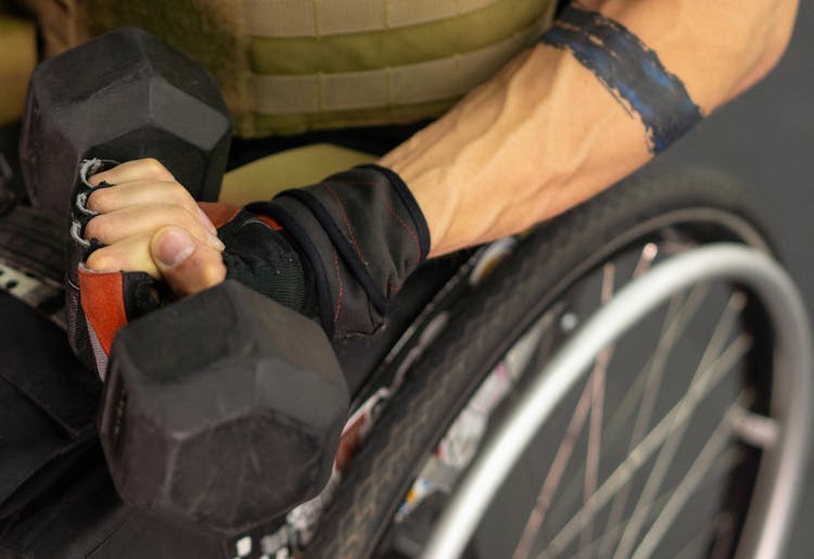 A Man In A Wheelchair Lifting A Dumbbell