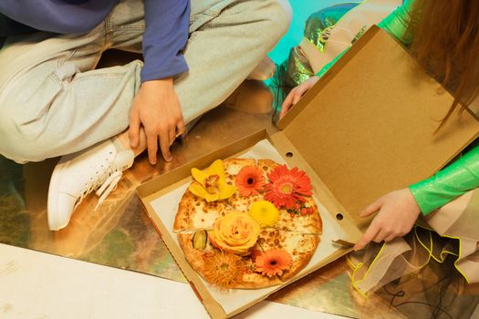 Creative pizza design with colorful flowers on a cardboard box, creating a unique culinary art piece.
