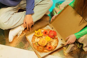 Two People Holding a Box of Pizza