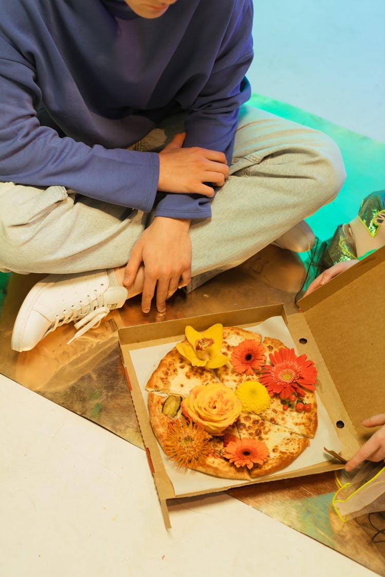 A Person Sitting Beside A Pizza