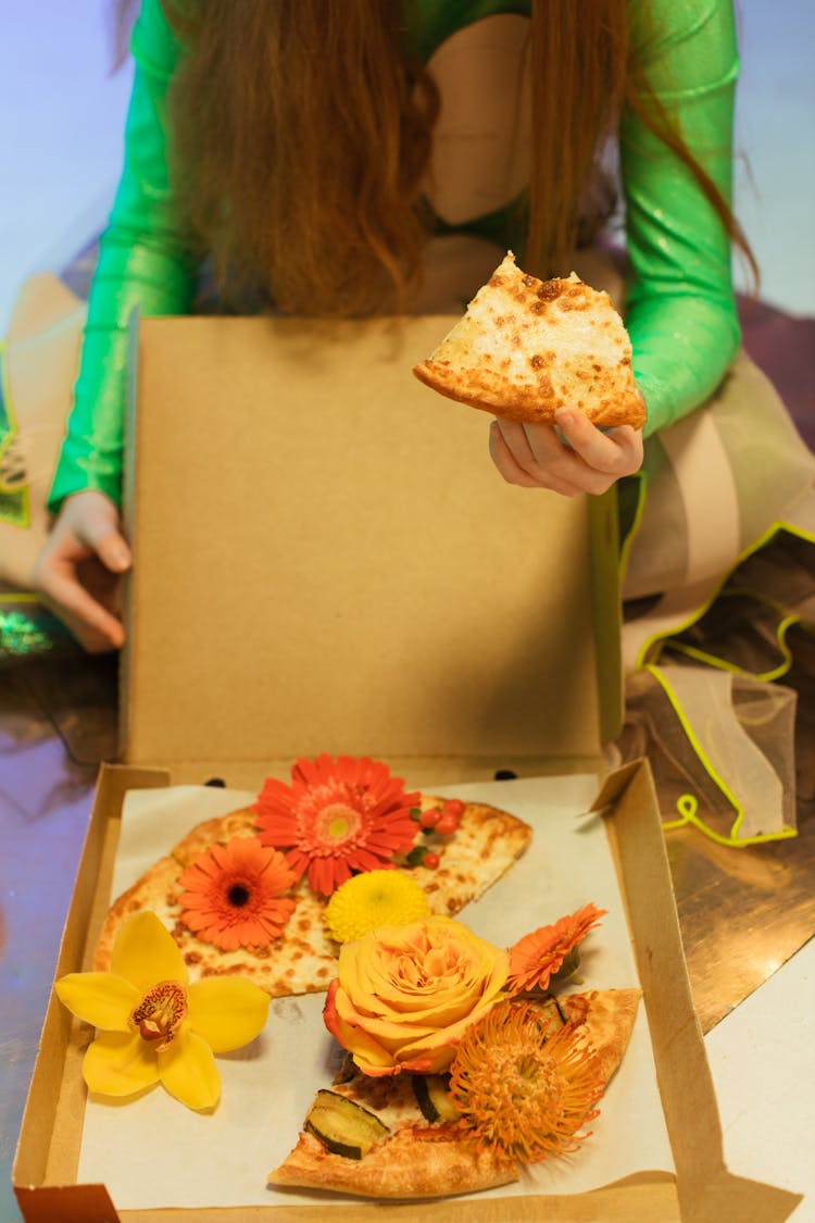 A Person Holding A Slice Of Pizza