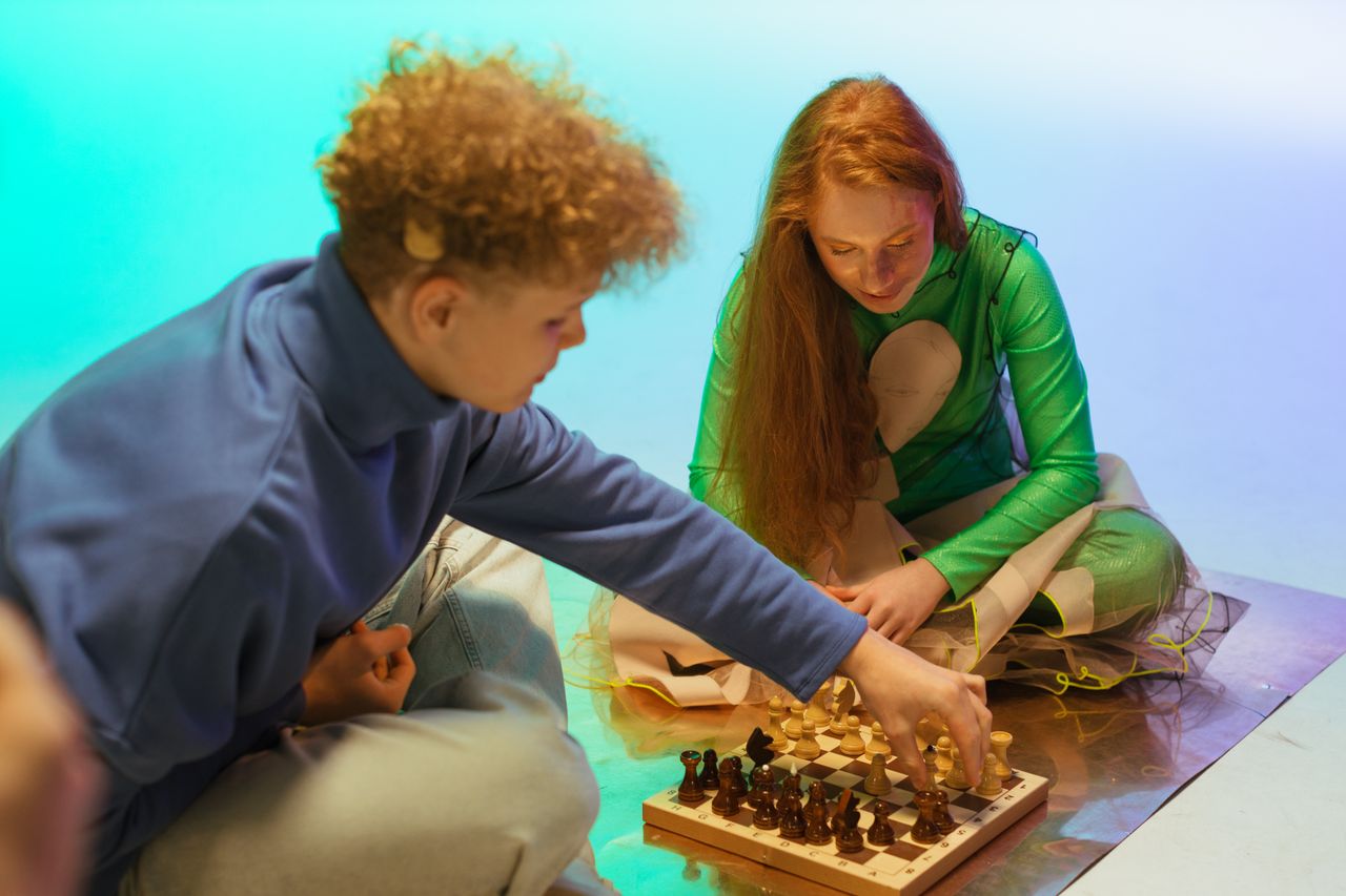two teenagers playing chess on a colorful indoor setup focusing on str