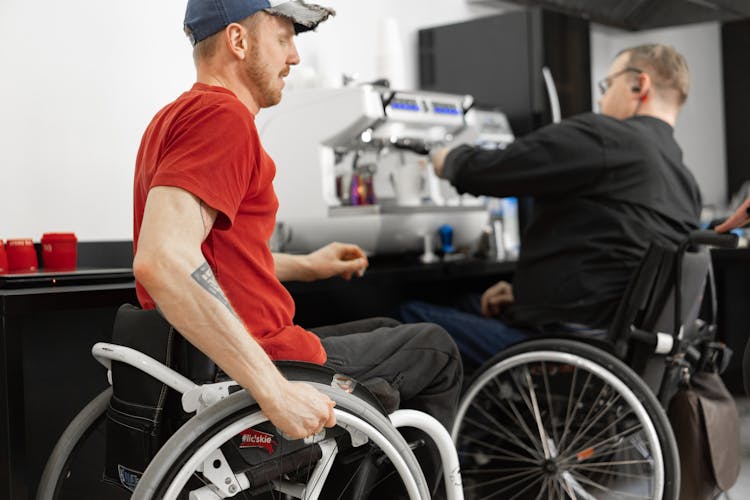 Men On Wheelchairs By Coffee Machine