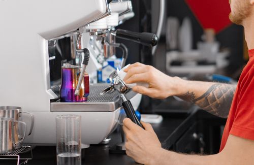 Free Close-up of a barista using an espresso machine to prepare coffee, showcasing professional technique. Stock Photo