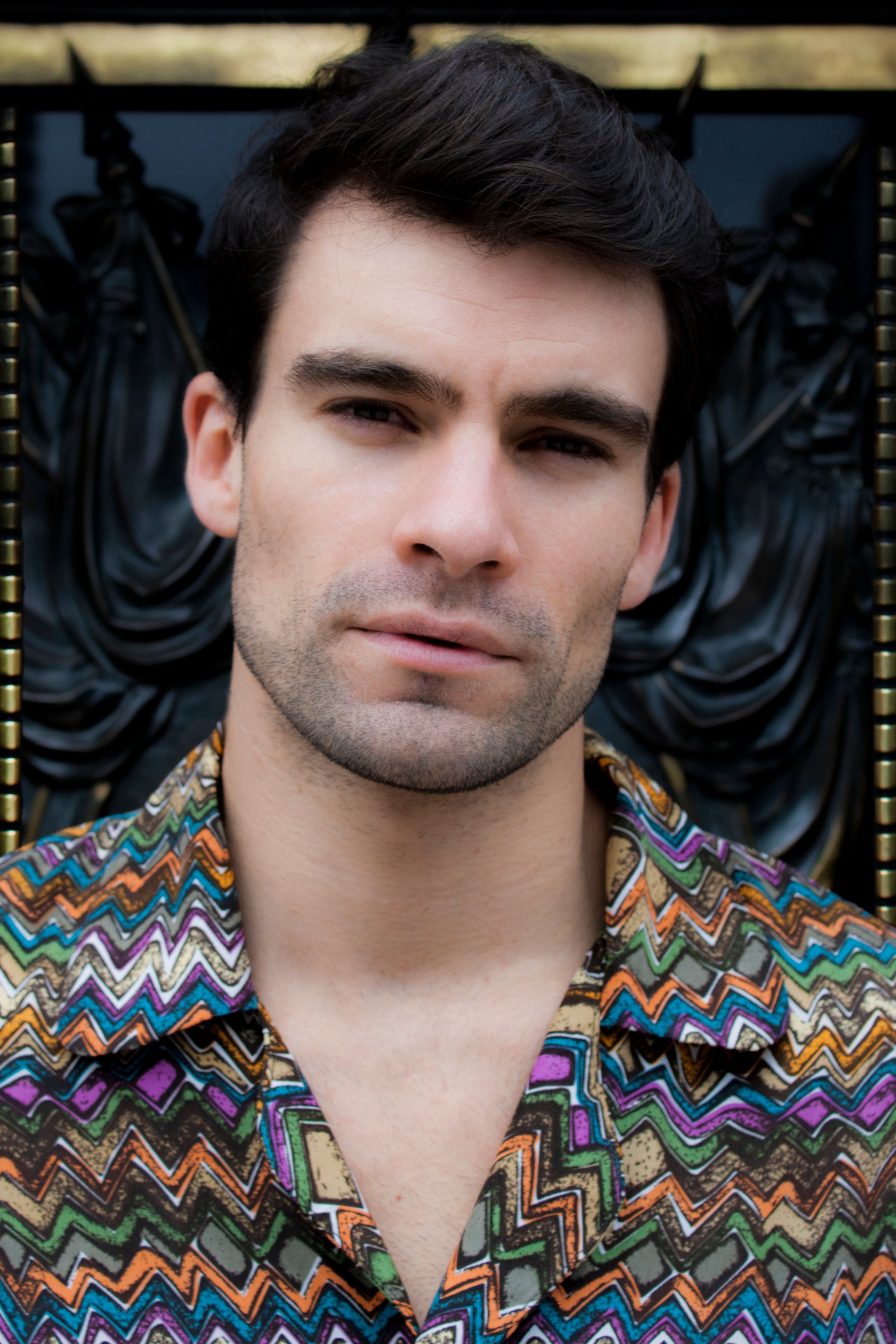Close-up portrait of a stylish man wearing a colorful patterned shirt, showcasing modern fashion and confidence.