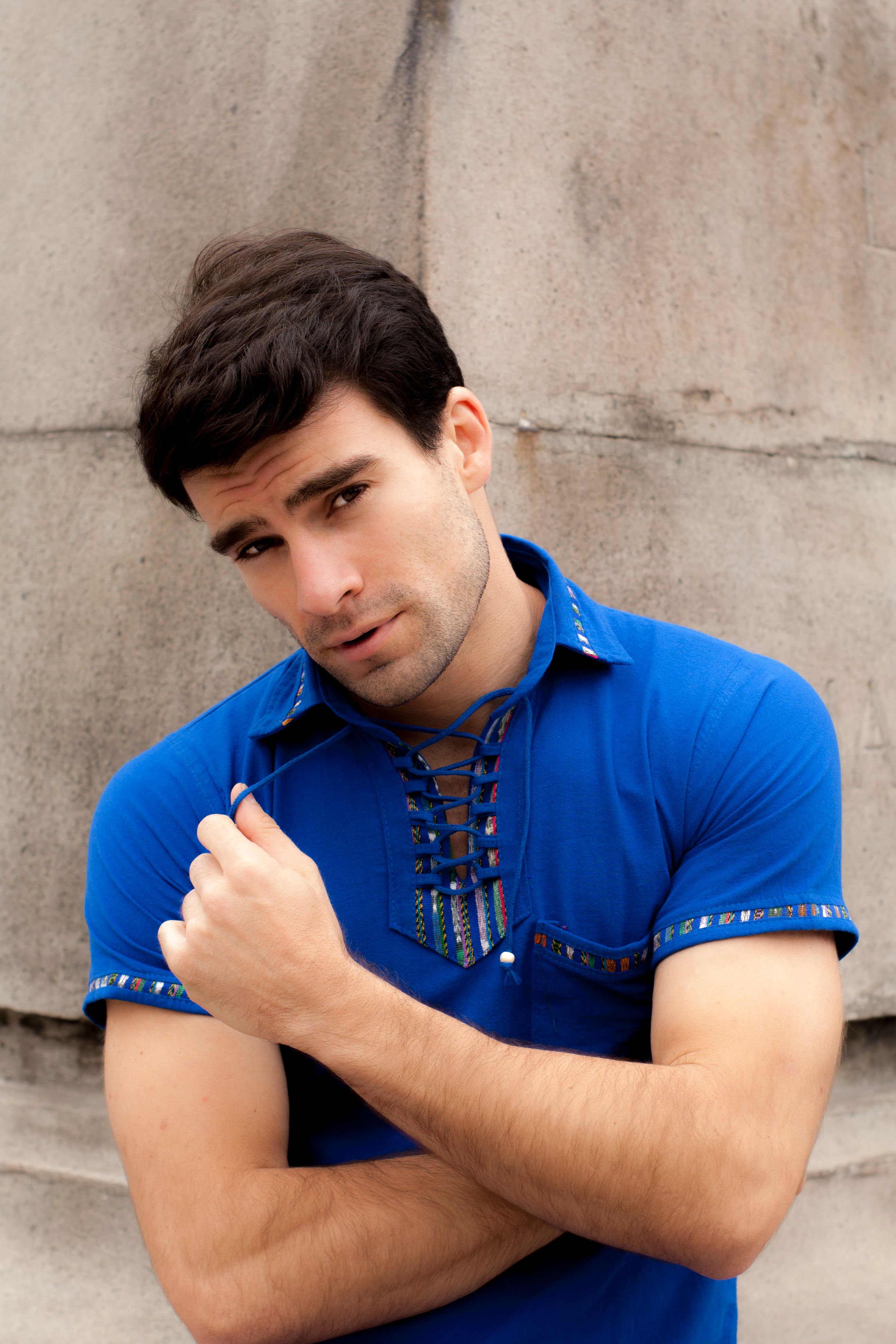 Fashionable young man in a blue shirt posing outdoors with confidence.