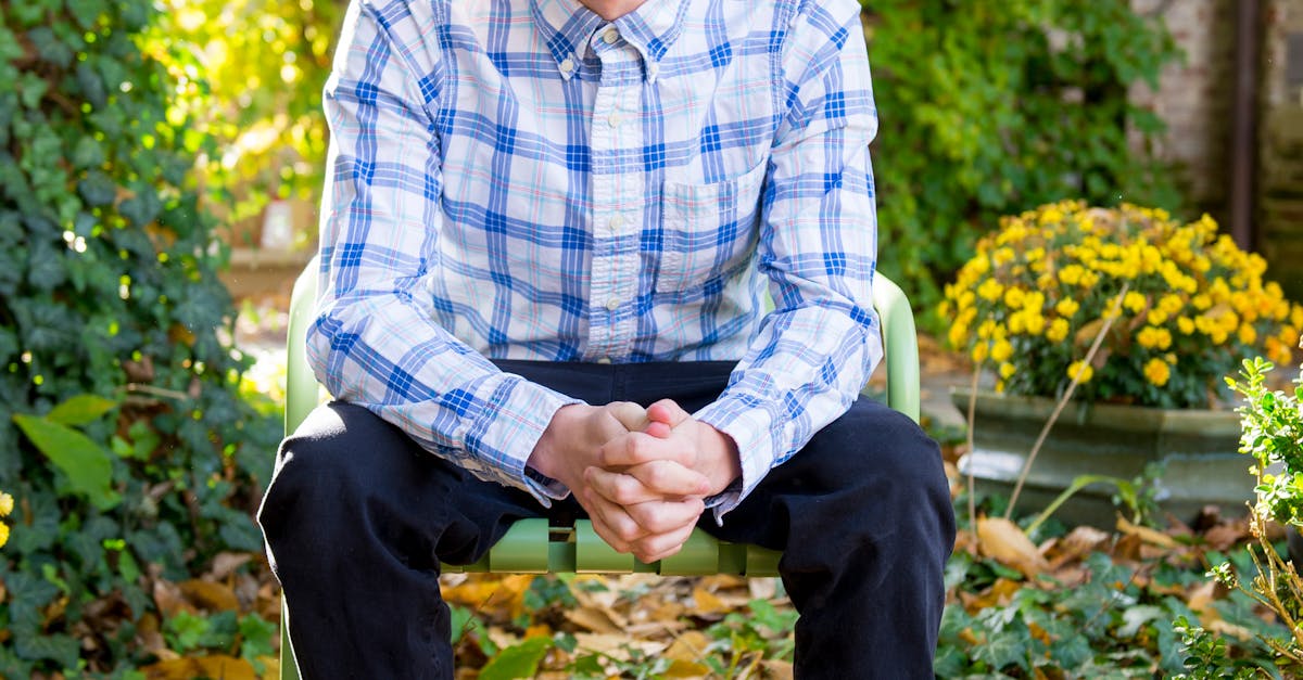 Man Wearing Blue and White Plaid Dress Shirt and Black Jeans Sitting on Green Chair