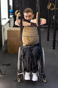 Athlete in wheelchair training with gymnastic rings, showcasing strength and determination indoors.