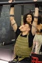 A Woman Supporting a Man in the Pull Up Bar