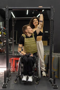 A man in a wheelchair receives supportive guidance from a fitness trainer at the gym.
