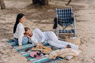 2 Women Sitting on Blue and White Textile on Beach
