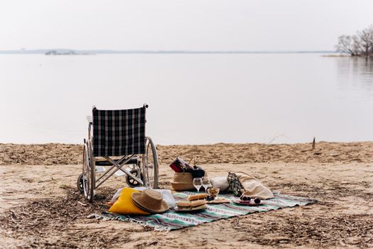 Wheelchair-accessible picnic by a serene beach with wine and snacks on a blanket.