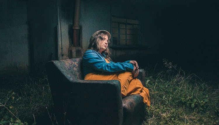 Woman Looking Up While Sitting On The Dirty Couch 