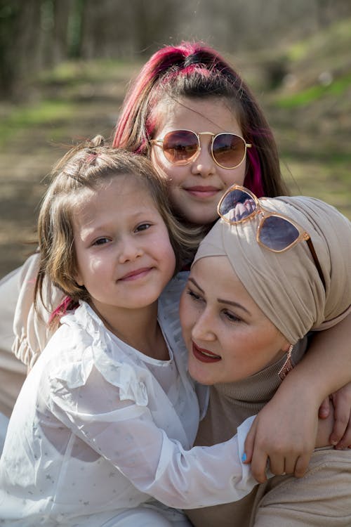 Ethnic mother in traditional headwear with cheerful daughters