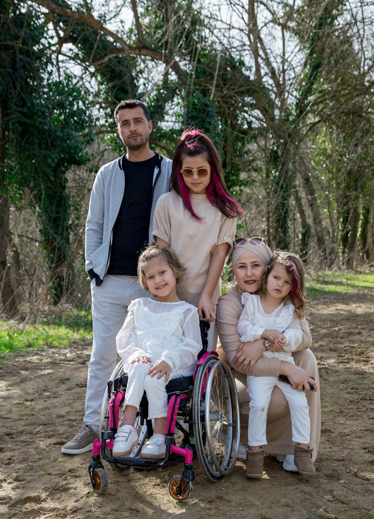 Happy Family With Girl In Wheelchair In Park