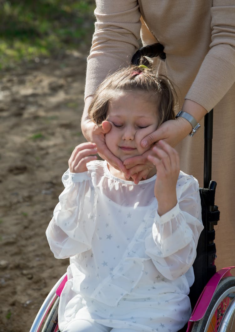 Mother Touching Cheeks Of Daughter In Wheelchair