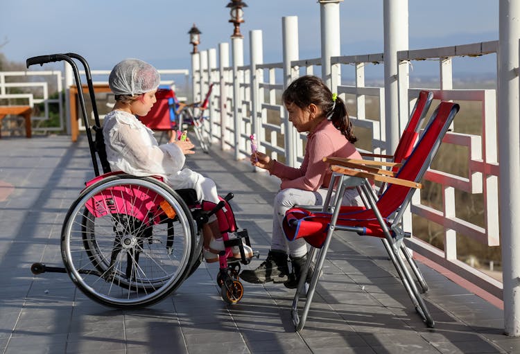 Girl In Wheelchair Talking With Friend