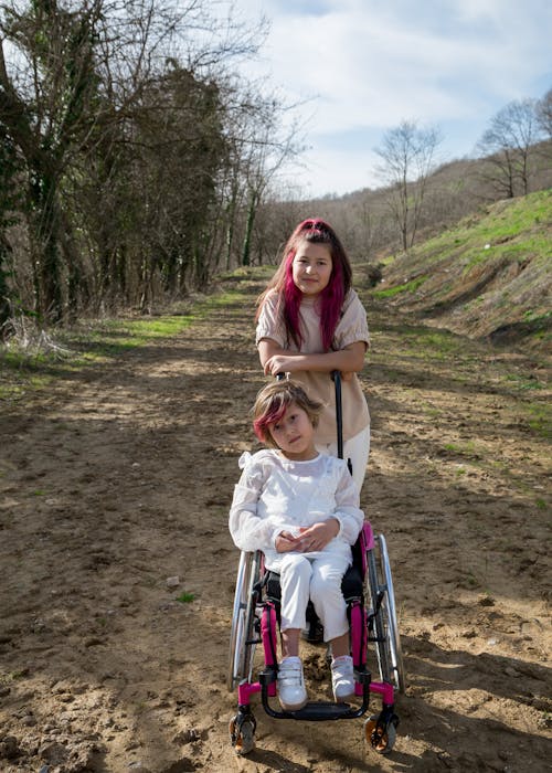 Free A Girl Standing at the Back of the Person Sitting on a Wheelchair  Stock Photo