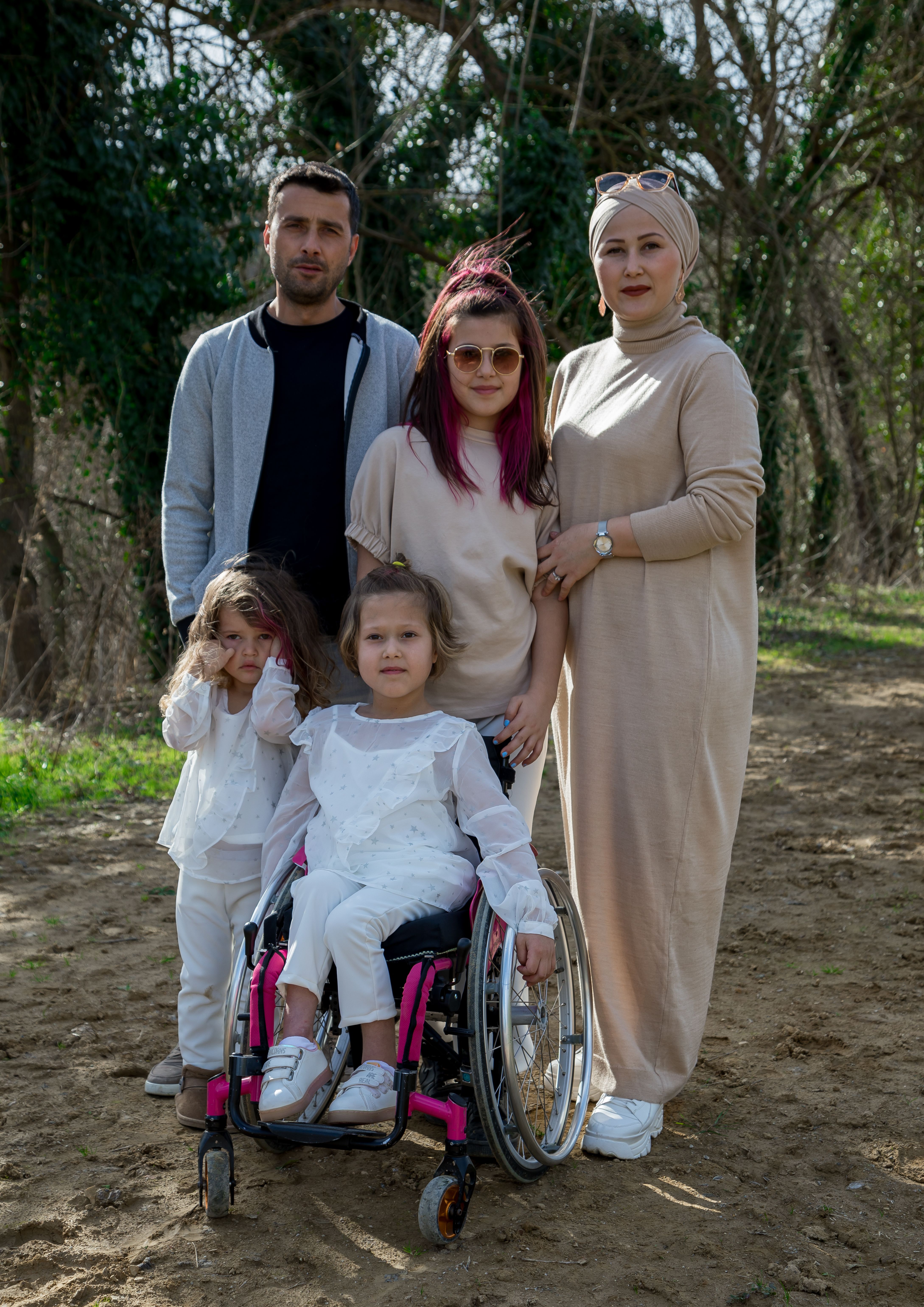 Happy family with grandmother in trendy hijab and headscarf in park with green trees