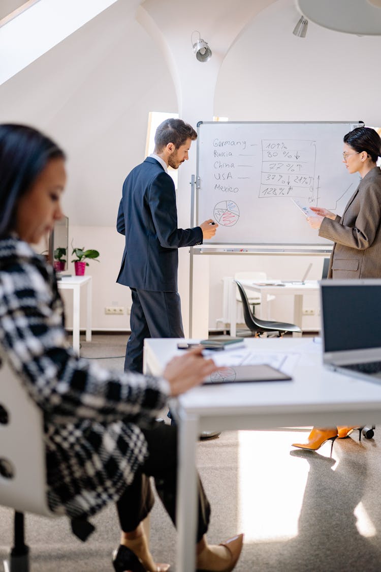 Man And Woman Standing Near The Whiteboard 