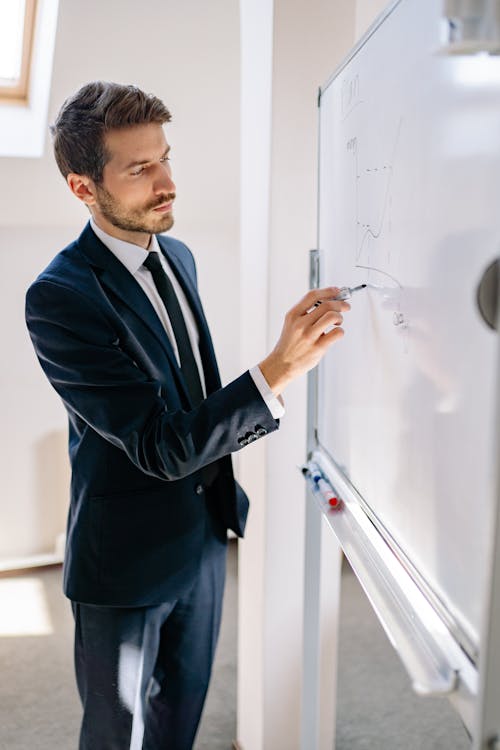 Man in Blue Suit Writing on Whiteboard